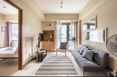 a living room with a couch and a mirror at 1 Bedroom Apartment Condo Across Manila Airport NAIA T3 in Manila
