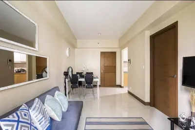a living room with a blue couch and a dining room at 1 Bedroom Apartment Condo Across Manila Airport NAIA T3 in Manila