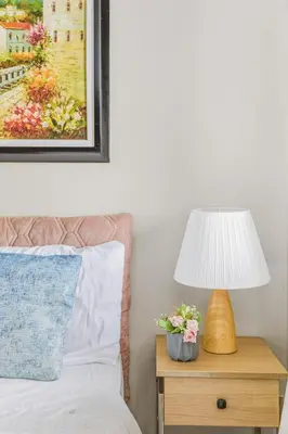 a bedroom with a bed with a lamp and flowers on a night stand at Admiral Baysuites 2602 in Manila