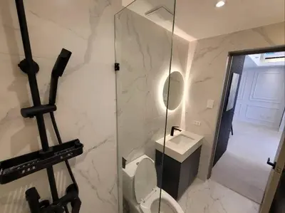 a bathroom with a toilet and a mirror and a sink at Staycation by Carmen Romualdo in Manila