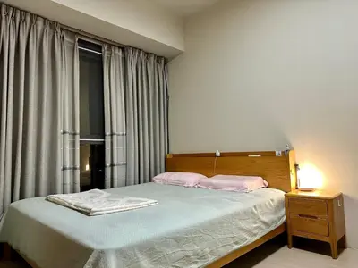 a bedroom with a bed with pink pillows and a window at Condotels by ZJM Residence in Manila