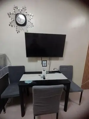 a table with chairs and a computer monitor on it at Sea Residences Pasay City MOA by Jhayem in Manila