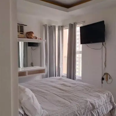 a bedroom with a bed with a television and a window at Manila bay view condo birch tower in Manila