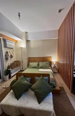 a bedroom with a large bed with green pillows at Cozy Studio at Venice Grand Canal Near BGC & NAIA in Manila