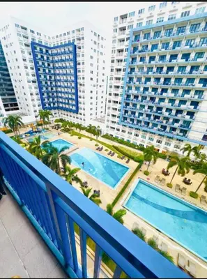 a balcony with two swimming pools and tall buildings at Melas Condotel in Manila