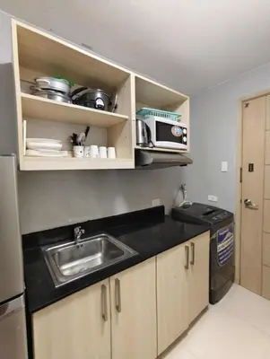 a small kitchen with a sink and a microwave at Staycation by Carlo and Chel's in Manila