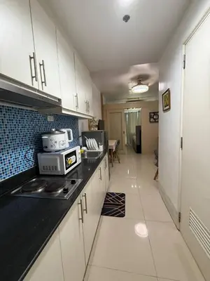a kitchen with white cabinets and a black counter top at Sea Residences Near MOA SMX Pasay City in Manila