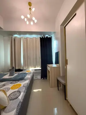 a bedroom with a bed and a desk and a window at Sea Residences Near MOA SMX Pasay City in Manila