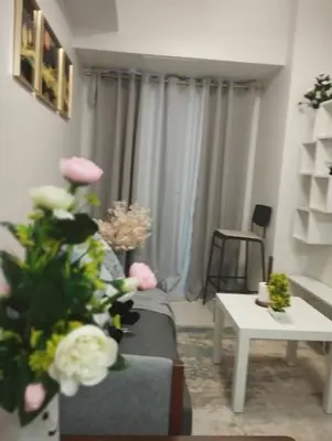 a living room with a couch and a table with flowers at Wowstaycation in Manila