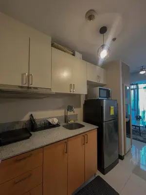 a kitchen with a sink and a refrigerator at Cozy Manhattan Araneta Cubao in Manila