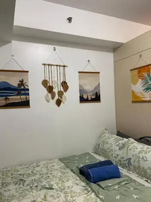 a bedroom with a bed and some pictures on the wall at Stern Home Stay at Sea Residences in Manila