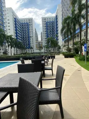 a row of tables and chairs with palm trees and buildings at Stern Home Stay at Sea Residences in Manila