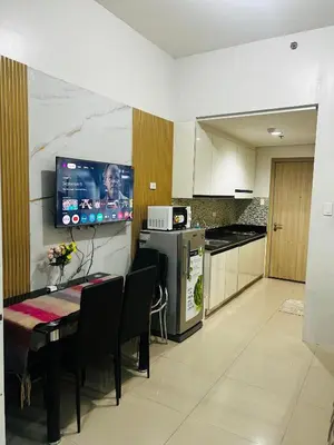 a kitchen with a table and a tv on the wall at Cozy Staycation at Shore Residences near Mall Of Asia MOA in Manila