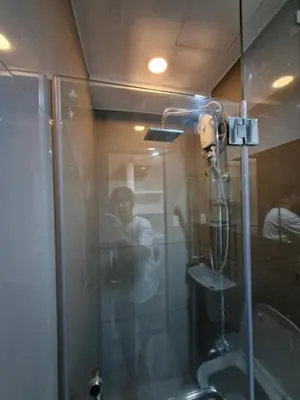 a shower in a bathroom with a man in the mirror at Spacious Makati Elite Air-2BR - Prime with City View in Manila