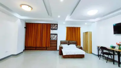 a living room with a bed and a table and a desk at Makati 2C Suite Room in Manila