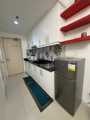a kitchen with white cabinets and a stainless steel refrigerator at Staycation By ABY Tower E Sea Residences in Manila