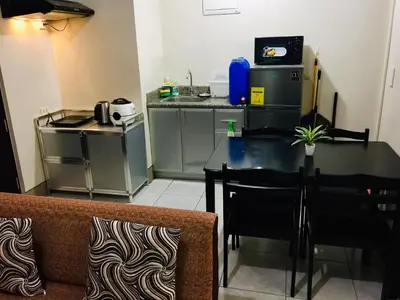 a living room with a table and a kitchen at Little Baguio Terraces in Manila