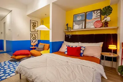 a bedroom with a bed and a yellow and blue wall at Modern Studio with Balcony near Ayala Makati in Manila
