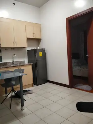 a kitchen with a refrigerator and a table in it at Paseo de Roces Condominium in Manila