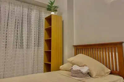 a bedroom with a bed with a wooden headboard and a window at Japandi Suite City Skyline View Condo Makati in Manila