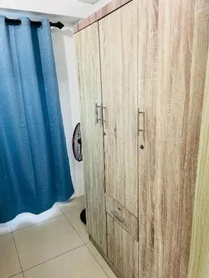 a pair of wooden cabinets in a room with a blue curtain at ESY Condotel shore 1-B in Manila