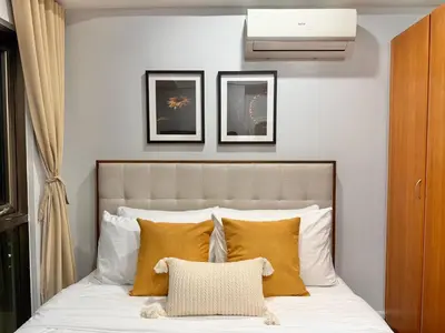 a bedroom with a bed with white and yellow pillows at Premier 3BR with Fast Internet near High Street BGC in Manila