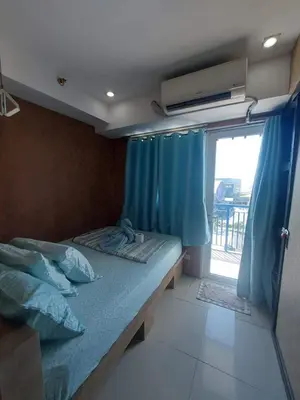 a bedroom with a bed with blue curtains and a window at The Barn at Sea Residences in Manila