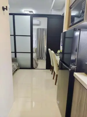 a kitchen with a refrigerator and a table with chairs at The Place To Be with Balcony and Kitchen Mandaluyong in Manila