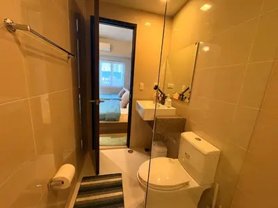 a bathroom with a toilet and a sink and a mirror at The Ellis Luxe Suites in Manila