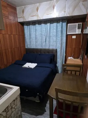 a bedroom with a bed and a table and a sink at nicecondotel in Manila