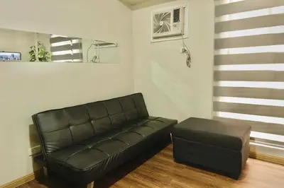 a living room with a leather couch and a stool at Chic Getaway Near Airport in Manila