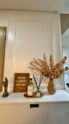 a shelf with a bottle of perfume and a plant at Warm & Homey Staycation Suite in Manila