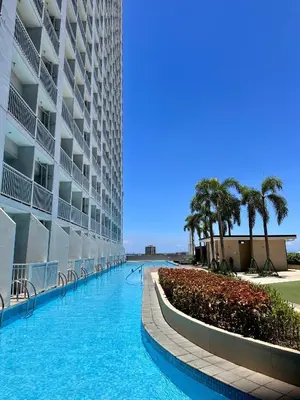 a swimming pool next to a building with palm trees at Warm & Homey Staycation Suite in Manila