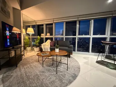 a living room with a couch and a table and a tv at High View Suite in BGC with Swimming Pool in Manila