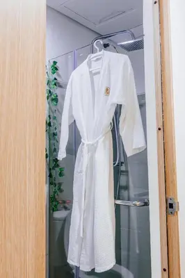 a white robe is hanging on a door at Shore Residence Tower A w Pool Near Airport and MOA in Manila
