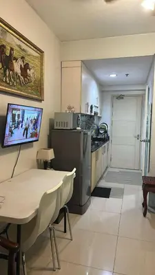 a kitchen with a table and a tv on the wall at MamiChai Place in Manila