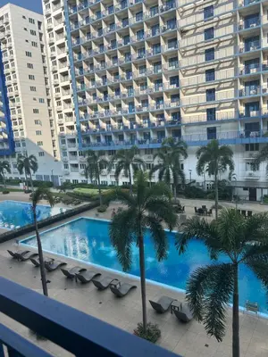 a view of a swimming pool with palm trees and a large building at MamiChai Place in Manila