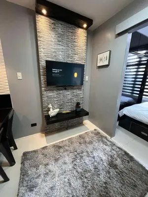 a living room with a flat screen tv on a brick wall at Antel Spa Residences 2602 in Manila