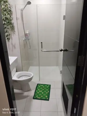 a bathroom with a shower and a toilet with a green mat at Gambino Homes in Manila