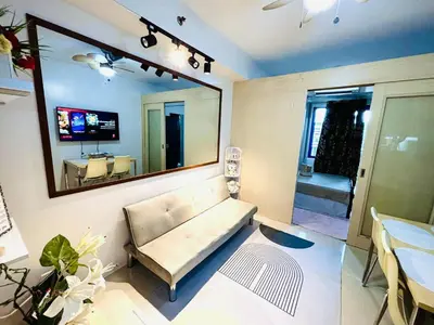 a living room with a couch and a large mirror at RE Staycations MOA VIEW in Manila