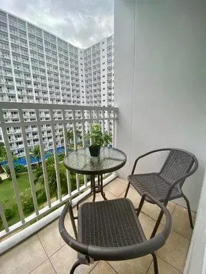 a table and chairs on a balcony with a large building at Dayontabalay in Manila