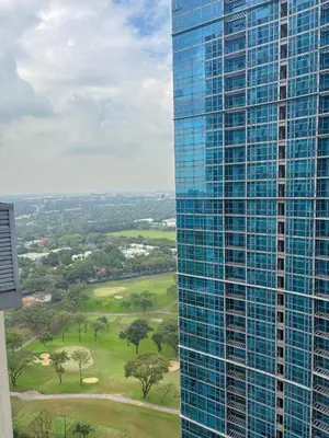 a tall glass building next to a golf course at PrimeStay BGC in Manila