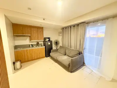 a living room with a couch and a kitchen at Stylish New Condo at Covent Garden Sta Mesa in Manila