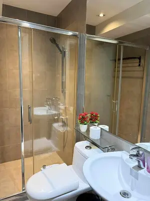 a bathroom with a shower and a toilet and a sink at The Gramercy Residences in Manila
