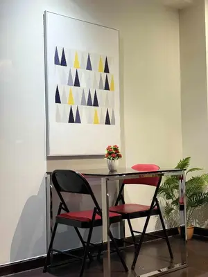 a table with two chairs and a painting on the wall at The Gramercy Residences in Manila