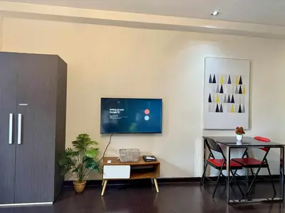 a living room with a table and a tv on a wall at The Gramercy Residences in Manila