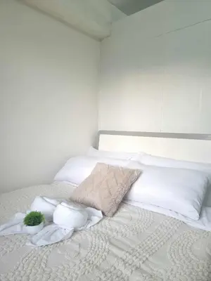 a white bed with white pillows and plants on it at 963 D shore 1 in Manila