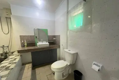 a bathroom with a toilet and a sink and a mirror at Layover Guesthouse in Manila