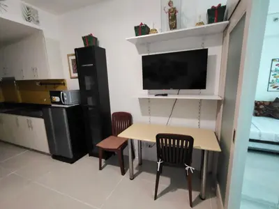 a kitchen with a table and two chairs and a tv at Sea Residences By Jervis in Manila