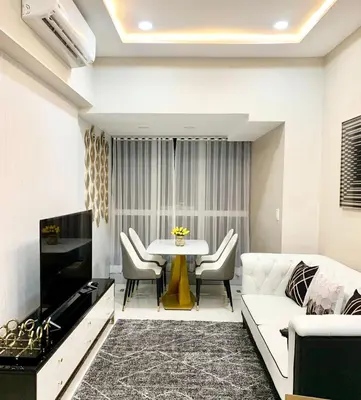 a living room with a white couch and a table at Cozy Apartment with Private Room in Vibrant Taguig in Manila